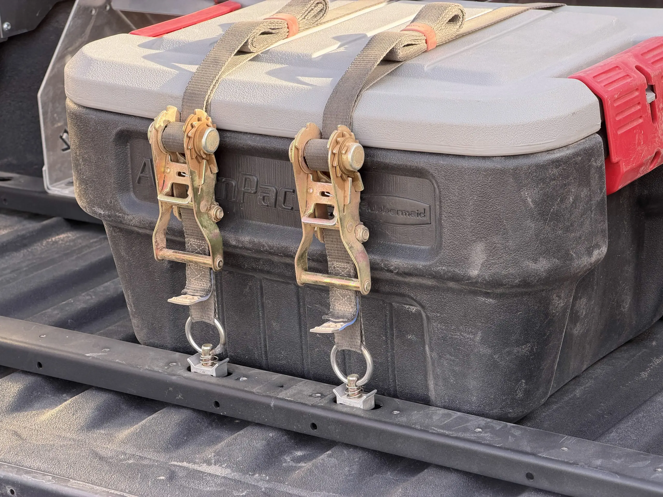Two Single Stud tie-down rings installed in BASE rails, anchoring ratchet straps around a cooler