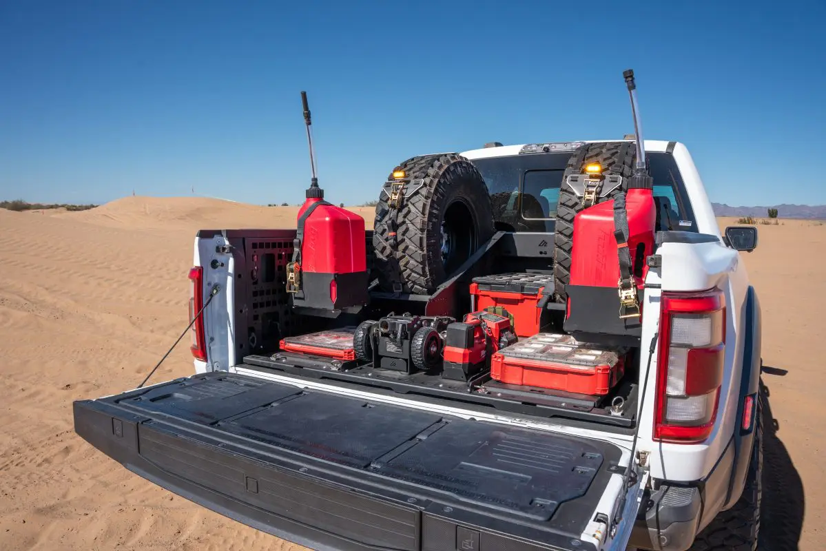 Angled desert view of an F-150 BASE setup with center tray, rear PACKOUT storage and dual VSTMs